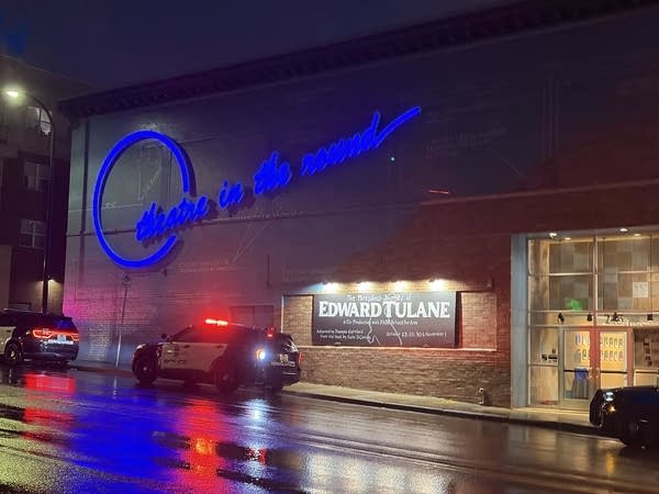 Police cars with their lights on are parked on the street outside Theatre in the Round.