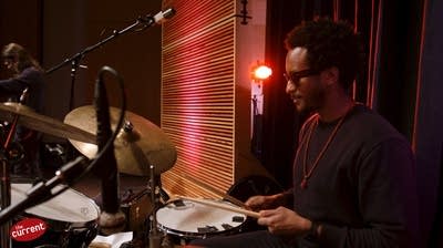 A musician plays drums in a small auditorium