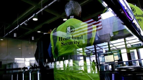 A person in a neon vest that says "Homeland Security."