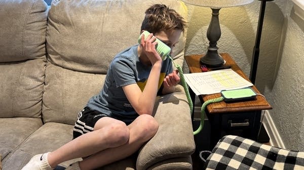 Jake Zobec, a Denver fourth-grader, speaks to his grandma on a landline telephone.