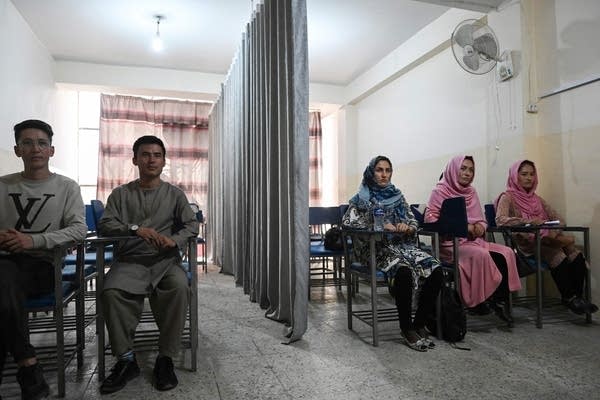 Male and female students attend a class at a private university in Kabul in September 2021. Male students sit on the left side, while women sit on the right, separated by a bifurcated curtain.