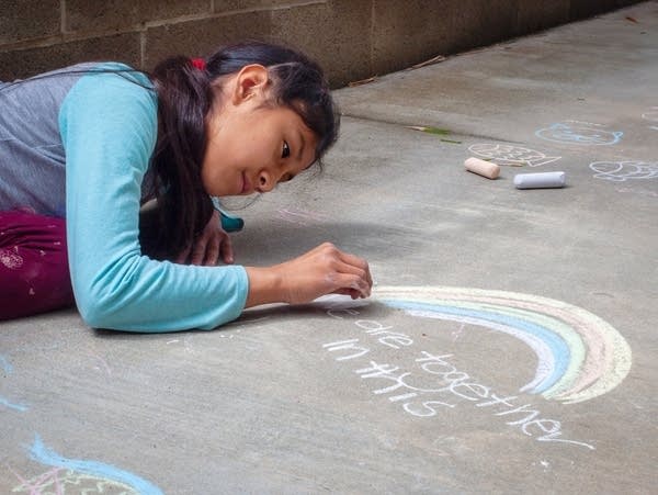 Girl drawing with chalk on the sidewalk