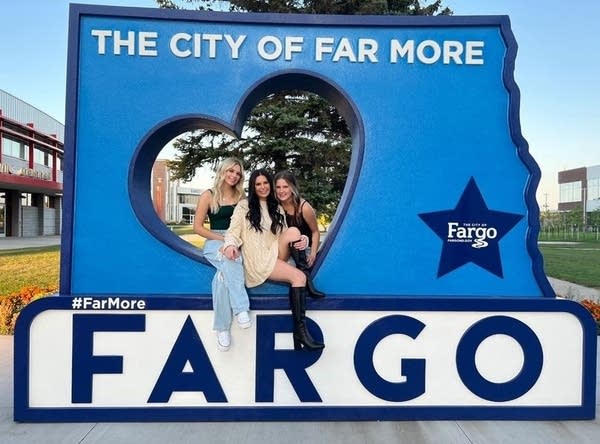 Three people pose in a landmark statue