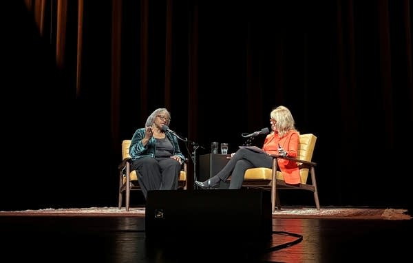 Two people talk on stage