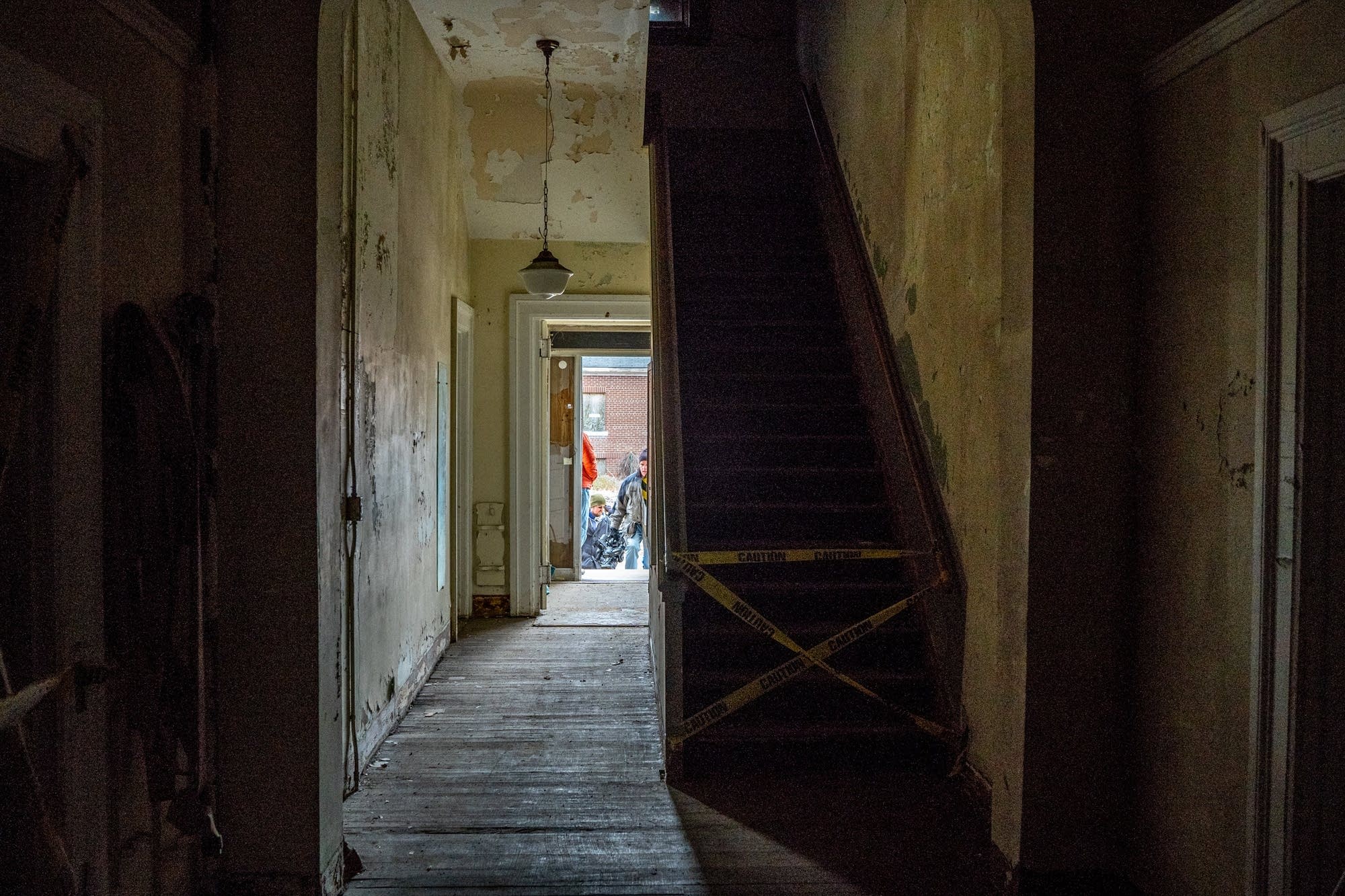 Caution tape blocks off a stairway inside of an abandoned building.