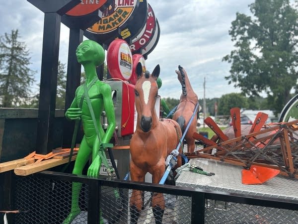 A number of yard ornaments, but at the front are a bright green aluminum alien and an aluminum horse.