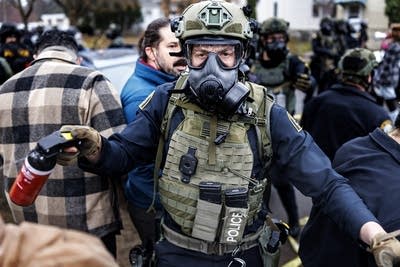An officer holds a can of pepper spray.
