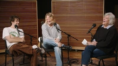 Three people have a conversation in a recording studio