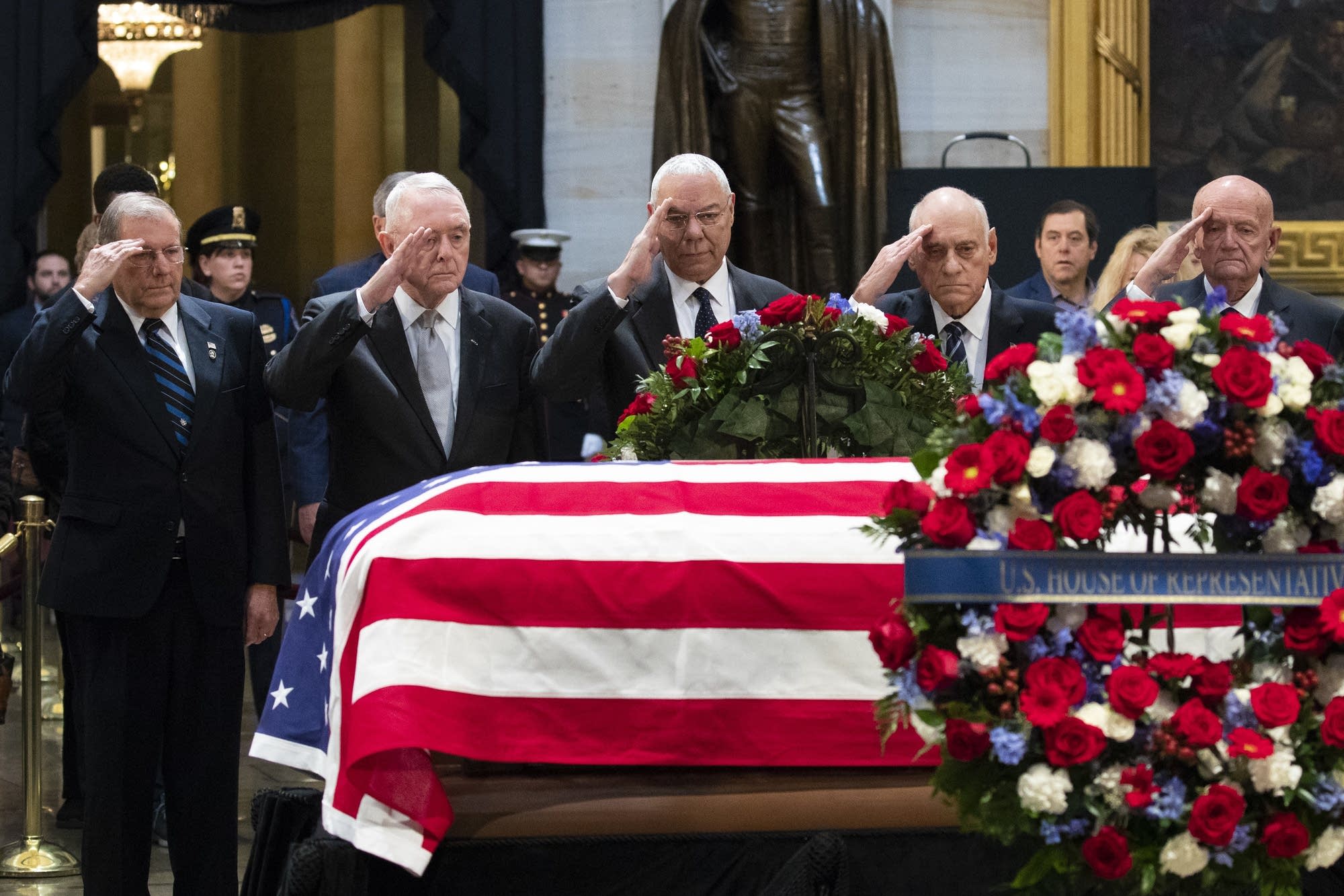Colin Powell and former military officials salute former President Bush.
