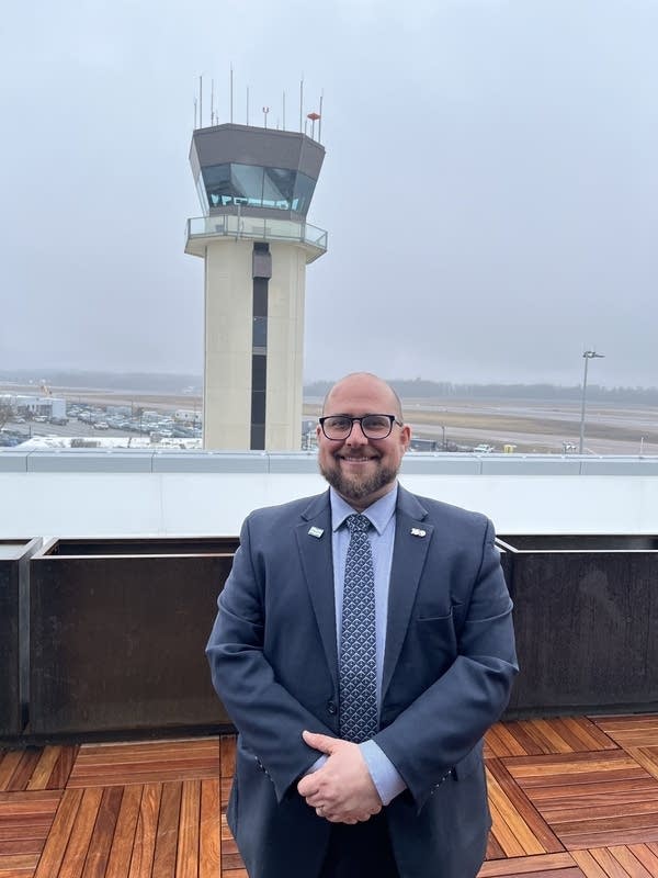 a man stands on an outdoor deck next to an air traffic control tower