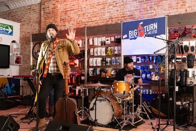Man singing into microphone with raised hand