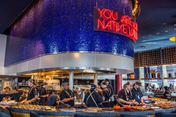 Staff work on food under a large sign that reads