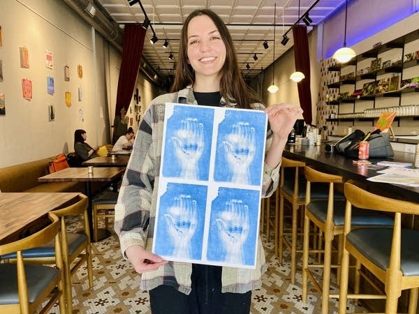 A woman holds up a print.