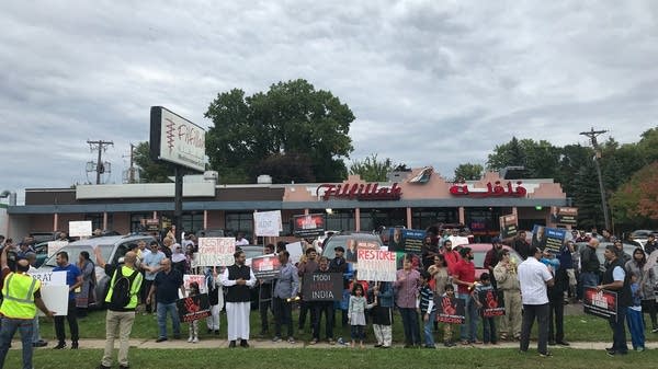 Protesters gathered outside Filfillah Mediterranean Grill holding signs.