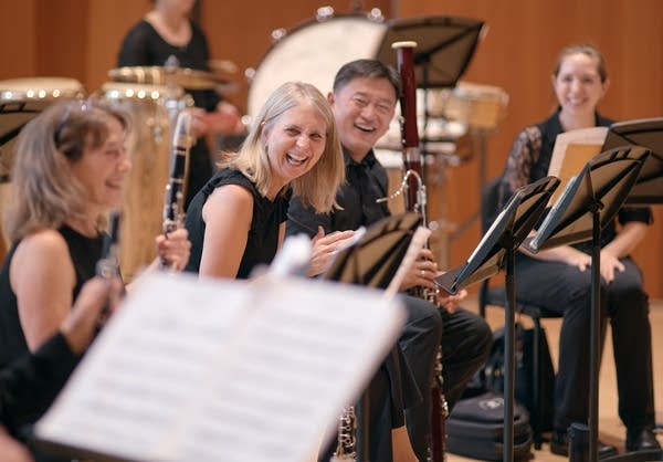 Musicians laugh as they rehearse in a performance space.