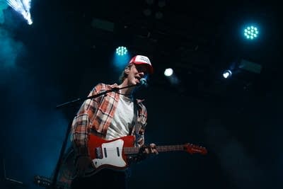 A man sings and plays guitar onstage