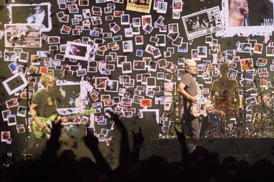 A rock band performing onstage in a large arena