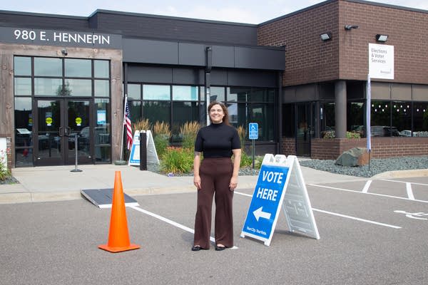 A woman stands outside of an early voting station.
