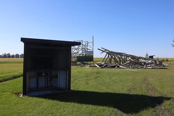A shed holding speakers is seen in the foreground in front of a collapsed drive-in screen.