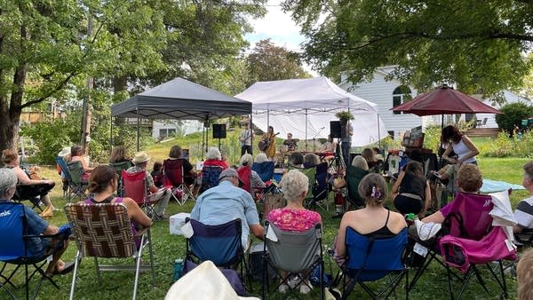 A band performing under a tent in a backyard