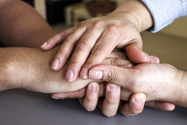 Two sets of hands clasp each other in embrace.
