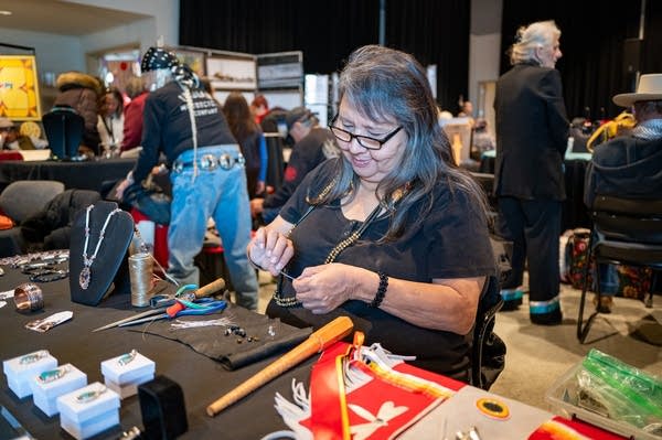A woman sits at a booth at a small business market.