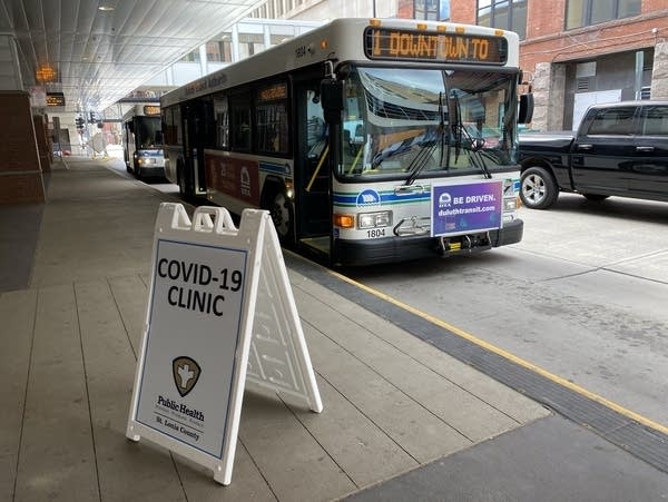 A sign sits near a street where a bus is parked.