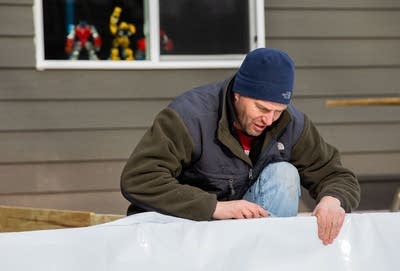 A man secures liner to boards. 