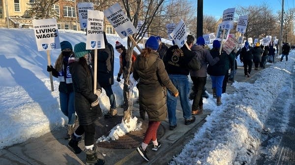 A group of teachers walk with picket signs.