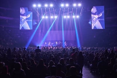 A rock band performing onstage in a large arena