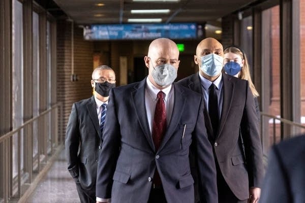 Three people walk down a skywalk.