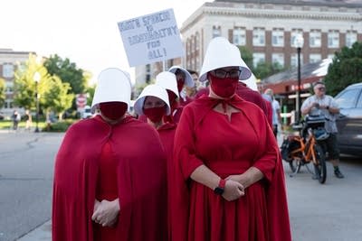People in red caps and dresses protest