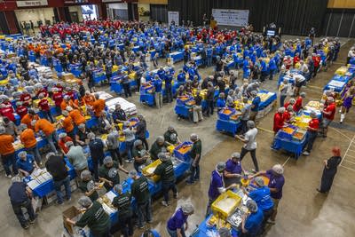 People stand at table and pack meals
