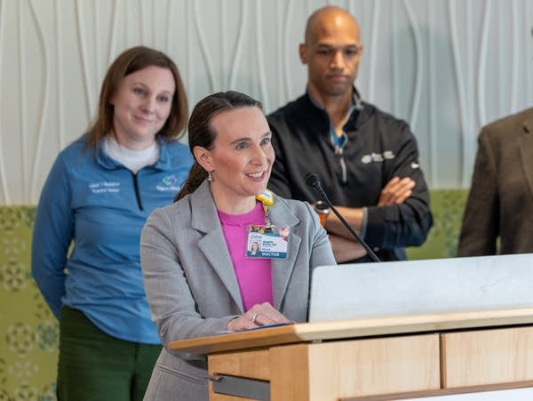 A woman speaks at a podium while other people look on