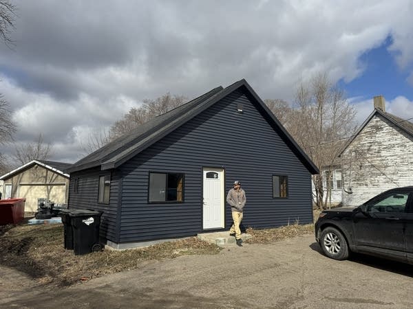 A man stands in front of a house