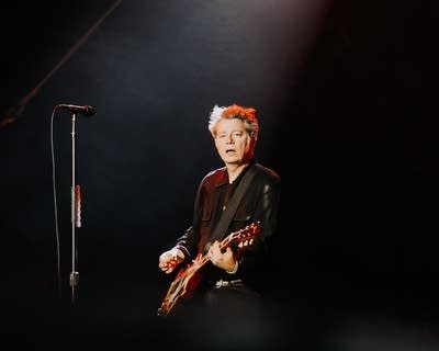 A musician plays guitar on a large outdoor stage