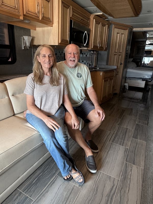 An older man and woman pose together inside an RV