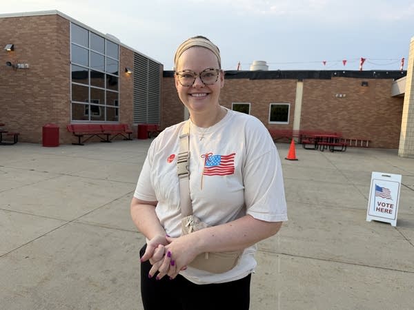 A woman stands outside of a polling place.