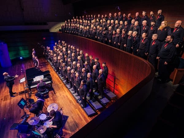 a large choir of men in black shirts and red ties