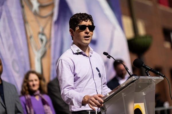 a man in sunglasses speaks at a podium