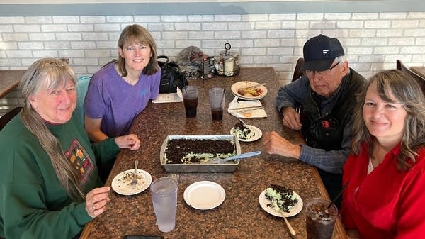 Four people sit around a table with Lime Jell-O Dessert.