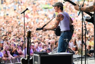 A musician sings and plays guitar on a large outdoor stage
