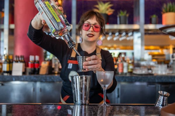 A woman pours a drink into a mixer.