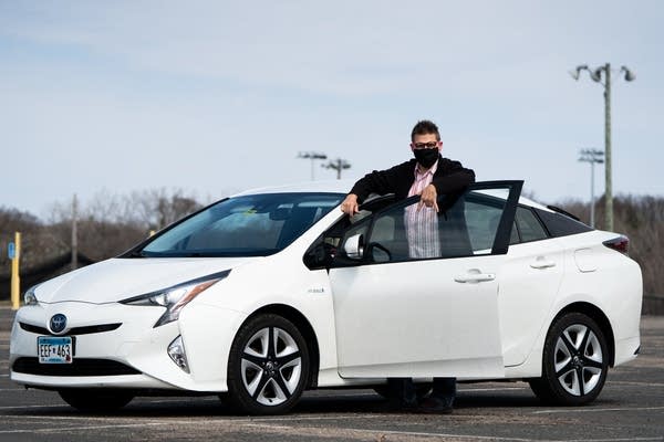 A man stands next to his white prius.