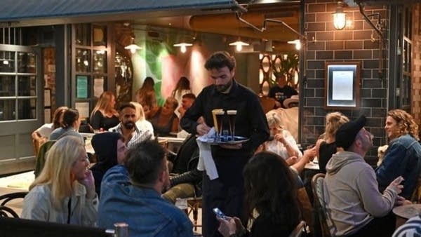 A waiter serves drinks to diners in the Soho area of London.