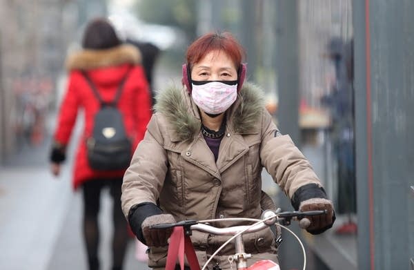 A woman wears a mask near the closed Huanan Seafood Wholesale Market, which has been linked to cases of coronavirus, in Wuhan, Hubei province