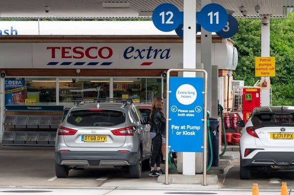 A person puts fuel in a car at a gas station