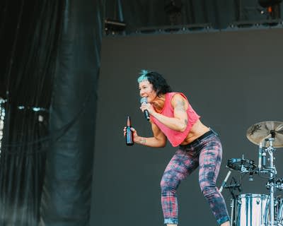 a woman singing and holding a bottle on stage