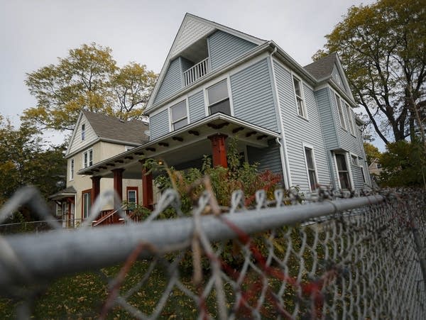 Chain-link fence surrounding blue two-story house.