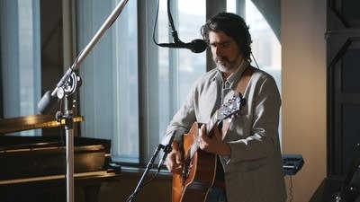 A musician plays guitar in a recording studio